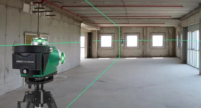 Láser de líneas cruzadas autonivelante proyectando ejes perpendiculares sobre el piso de una sala amplia.