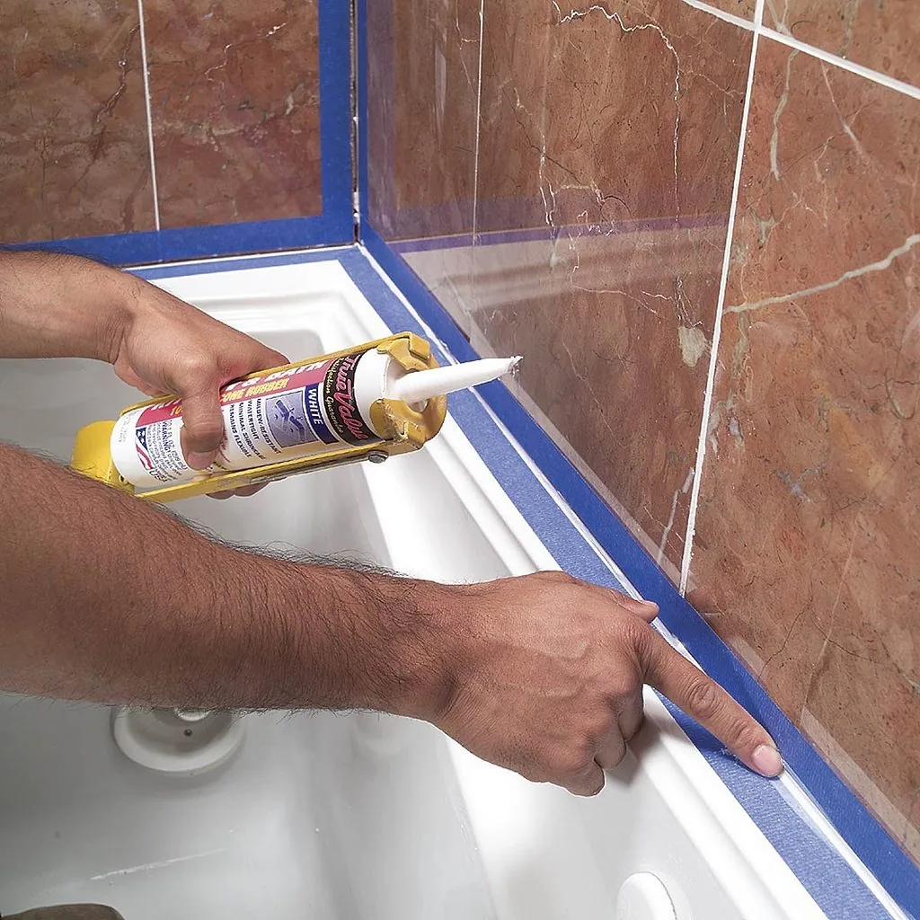 Cordón de silicona sellando el encuentro del piso con la pared y la base de la bañera en un baño.